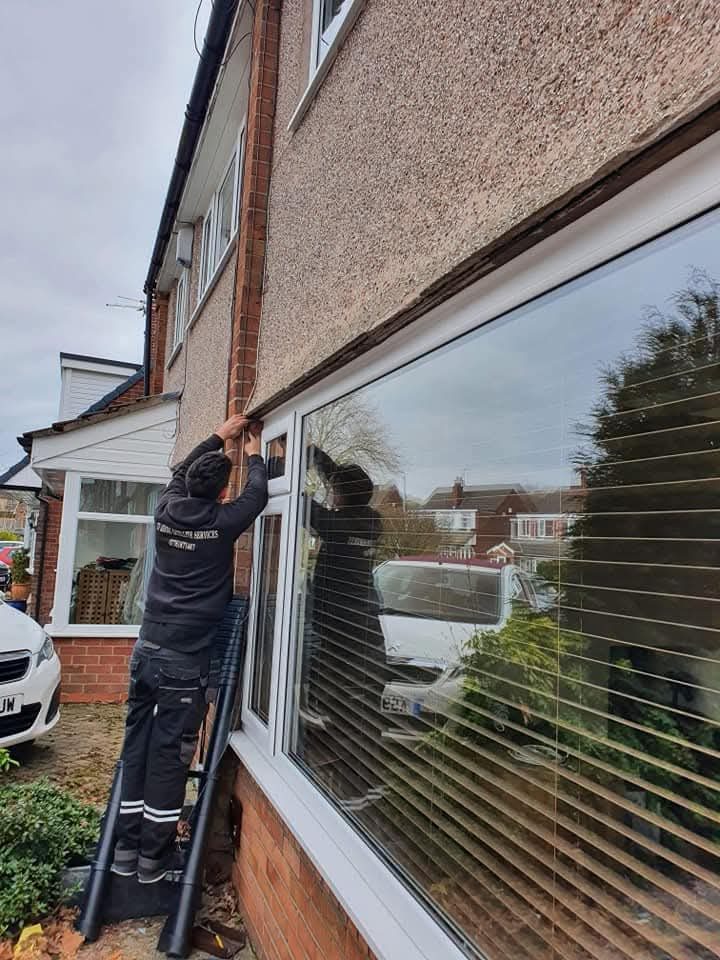 Engineer checking a coax cable and wall-plate connection while diagnosing why one TV has no signal and another still works