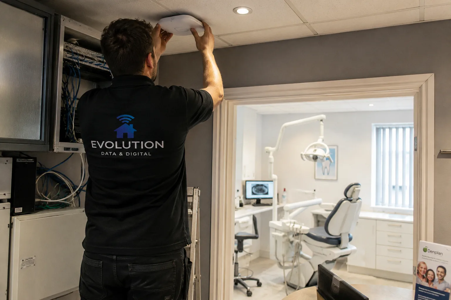 Evolution Data & Digital engineer working on a ceiling-mounted WiFi access point beside network equipment in a dental practice