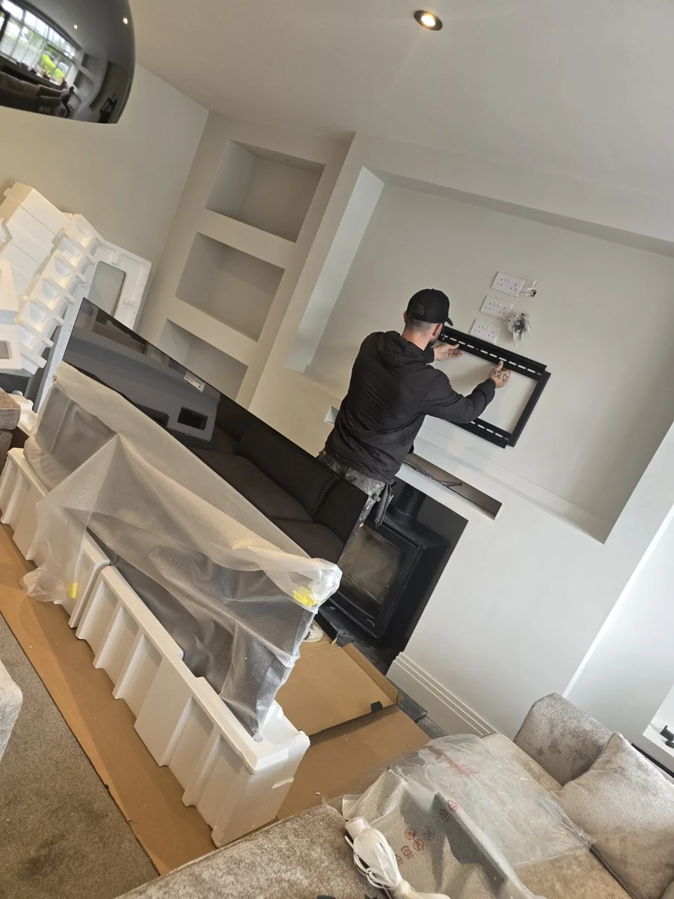 Engineer fitting a full-motion TV bracket to a media wall in Prestwich