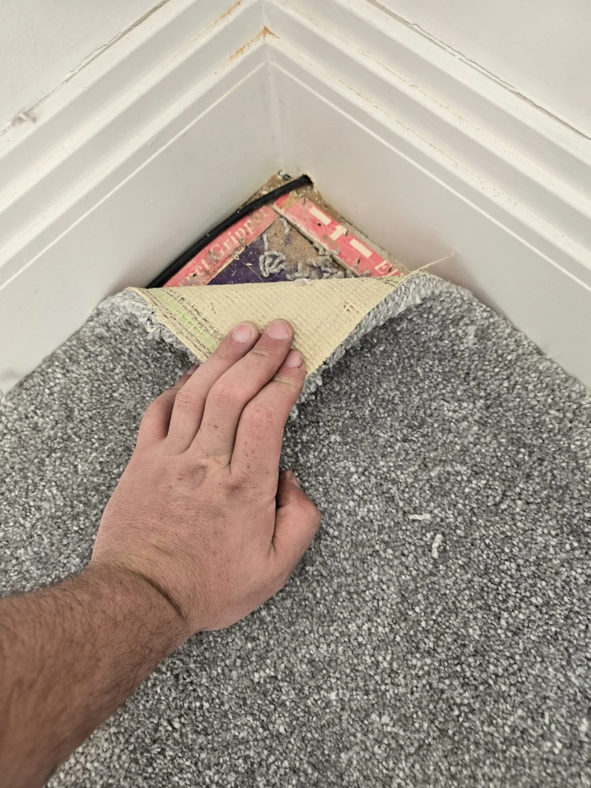 Carpet edge being lifted to conceal network cable in the Clock Face home