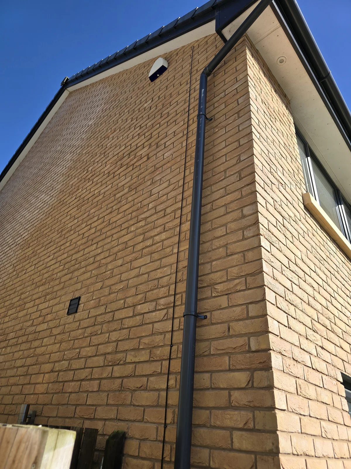 External black network cable routed beside a downpipe on the Clock Face new-build