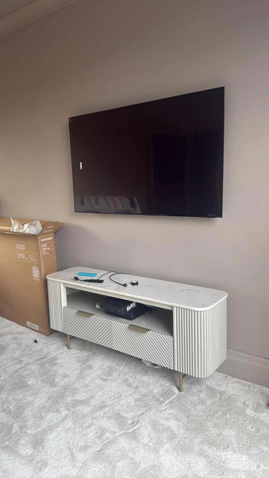 Wall-mounted television above a white media unit in a Manchester city-centre apartment