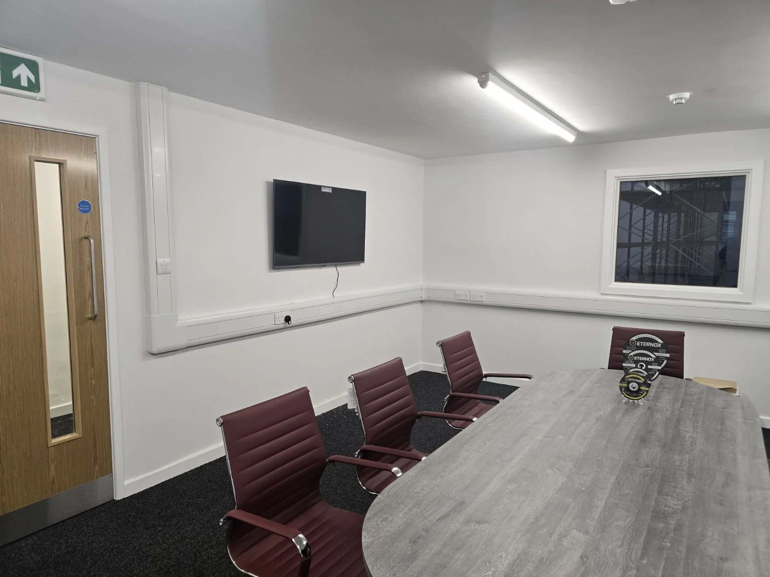 Wall-mounted display, meeting table and perimeter dado trunking in a Trafford Park office