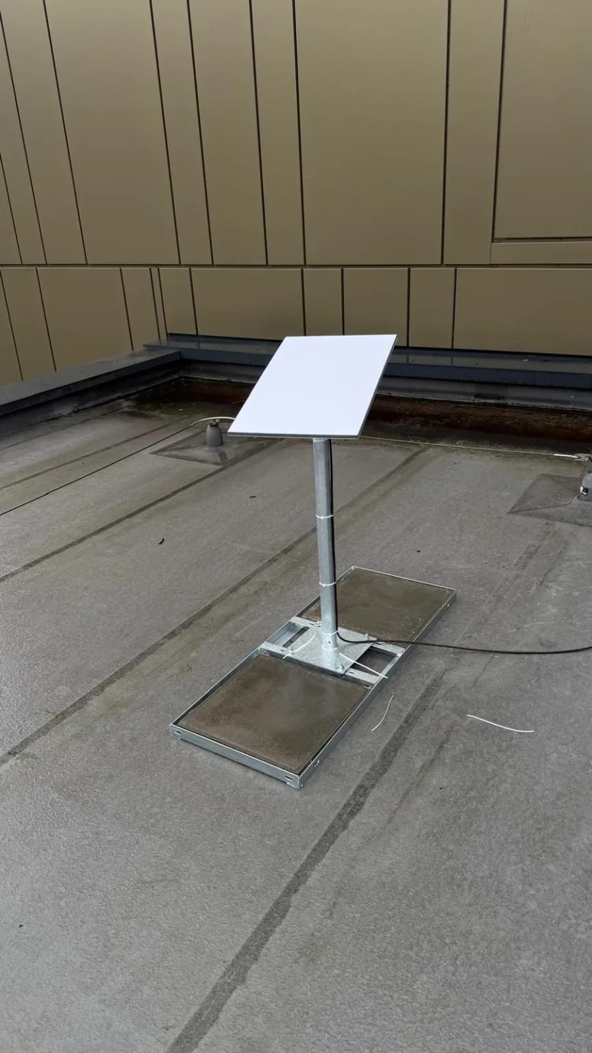 Starlink dish on a weighted non-penetrating flat-roof mount at a Manchester city-centre office