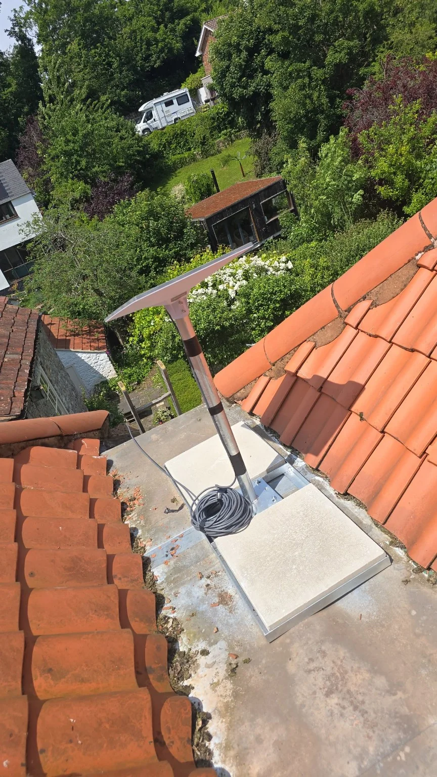 Starlink dish and weighted mounting frame between tiled roof sections at the Congleton home