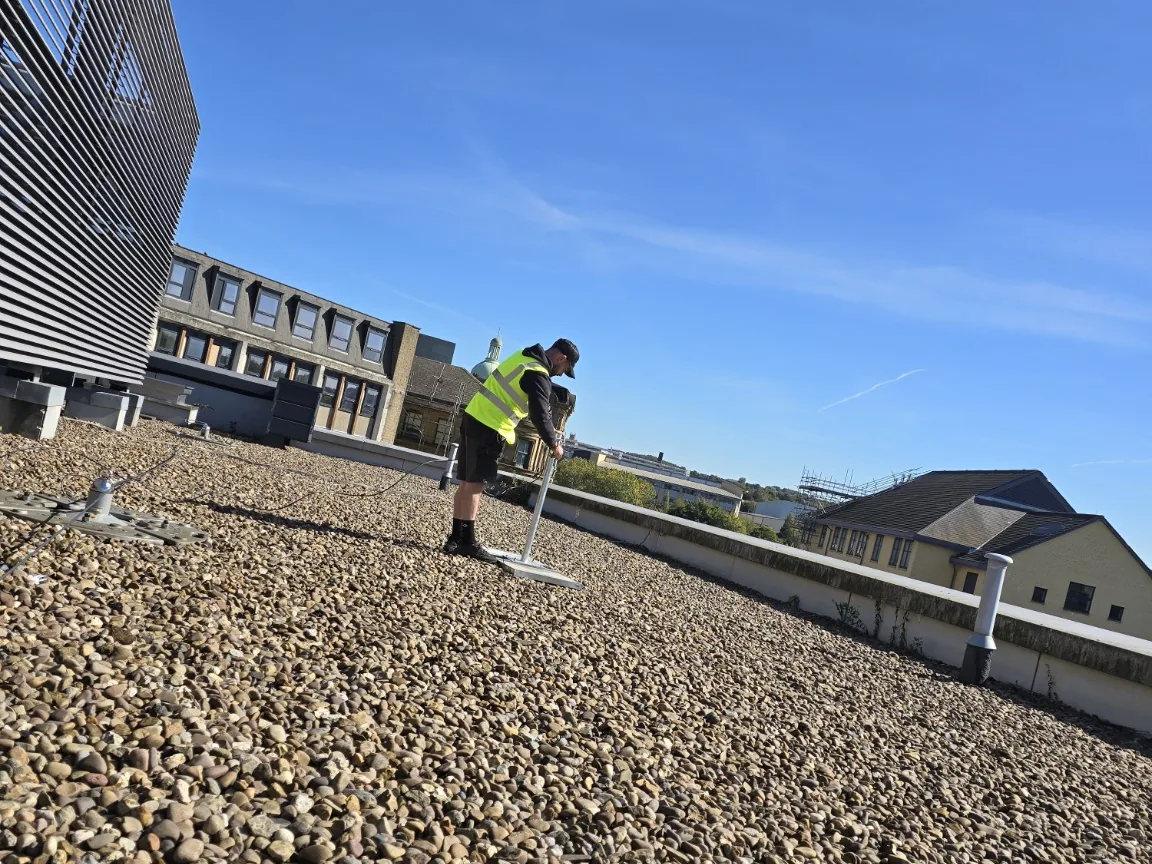Engineer positioning a weighted flat-roof TV aerial mount on a Bradford shopping-centre roof