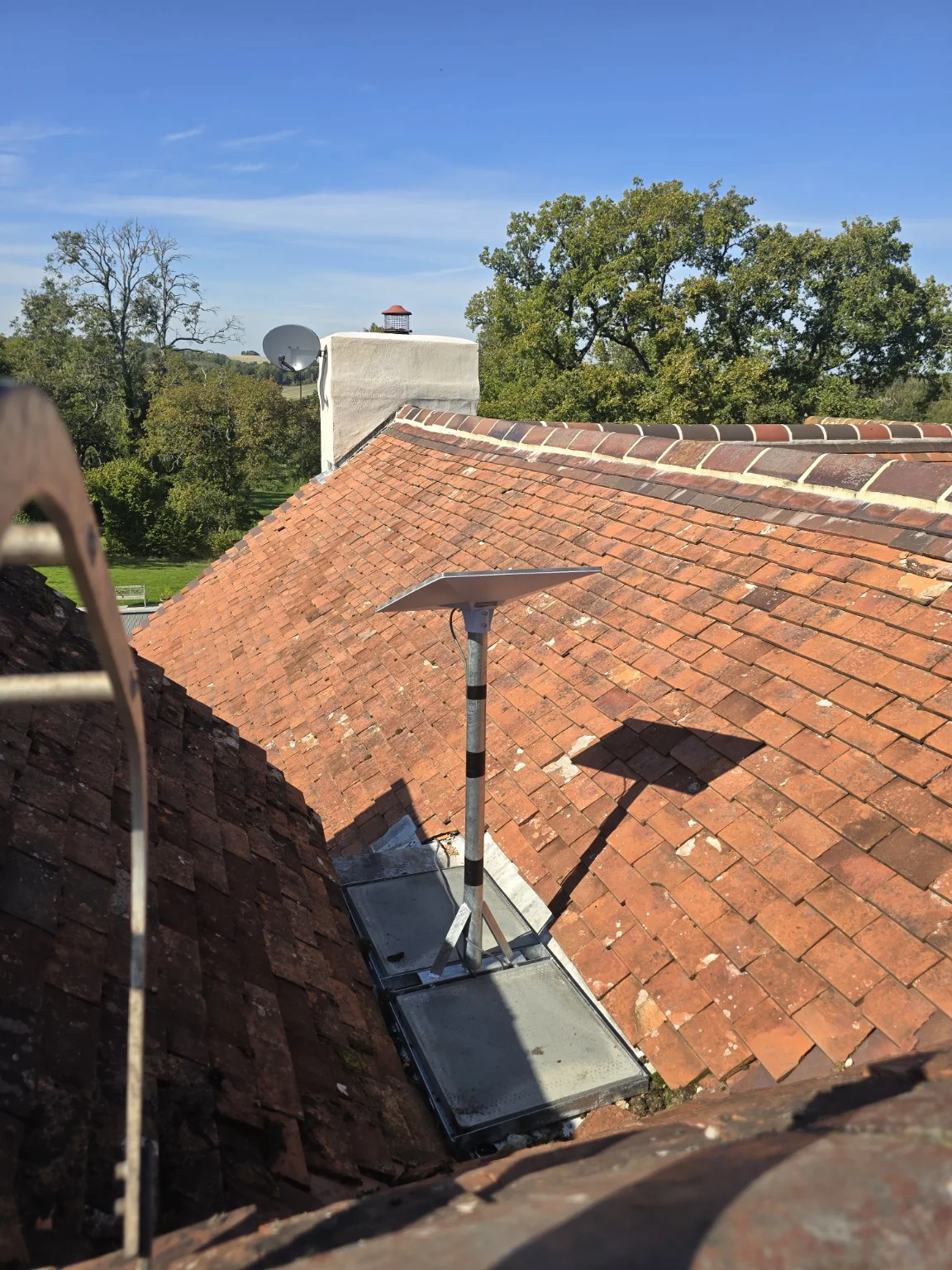 Starlink dish and concrete-weighted frame inside a tiled roof valley at an Alderley Edge home