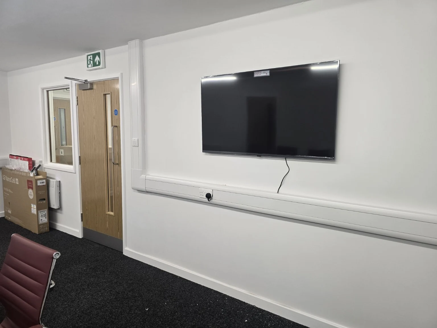 Wall-mounted meeting room display above office dado trunking in Trafford Park