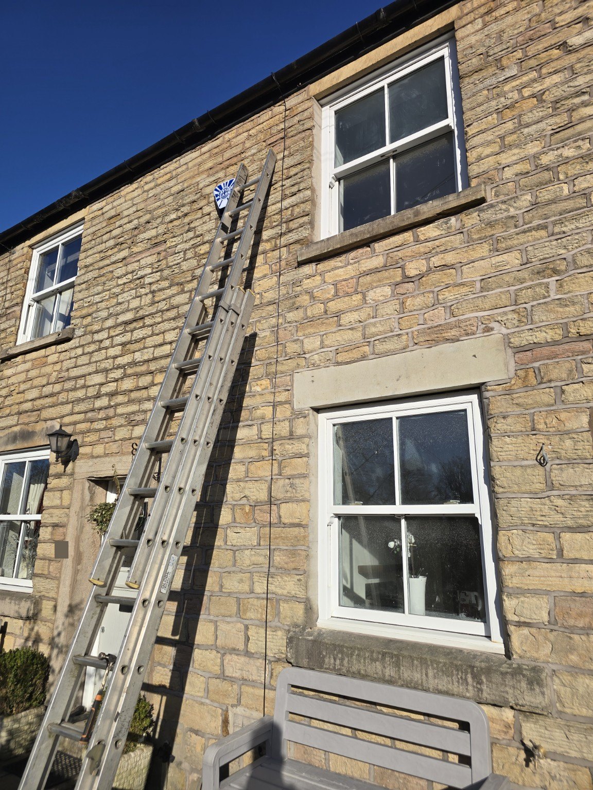 Neatly routed black coaxial television aerial cable secured vertically to a stone exterior wall.