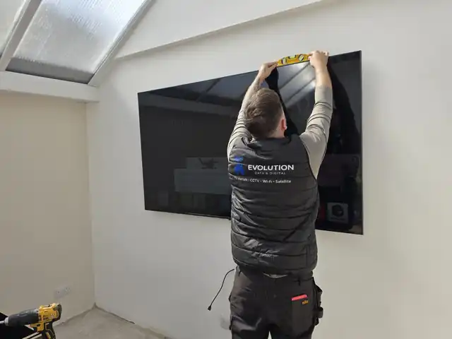 Evolution Data & Digital engineer levelling a wall-mounted TV during a genuine Cheadle installation